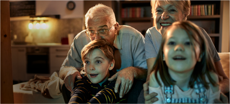 Photo of grandparents and children watching television during a power outage